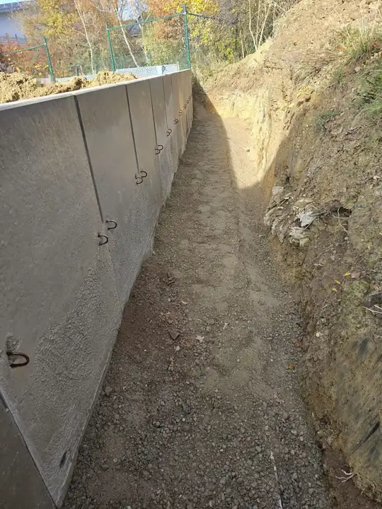 Stützmauer aus L-Steinen, Blick durch den offenen Graben entlang der Mauer, rechts die angeschnittene Böschung