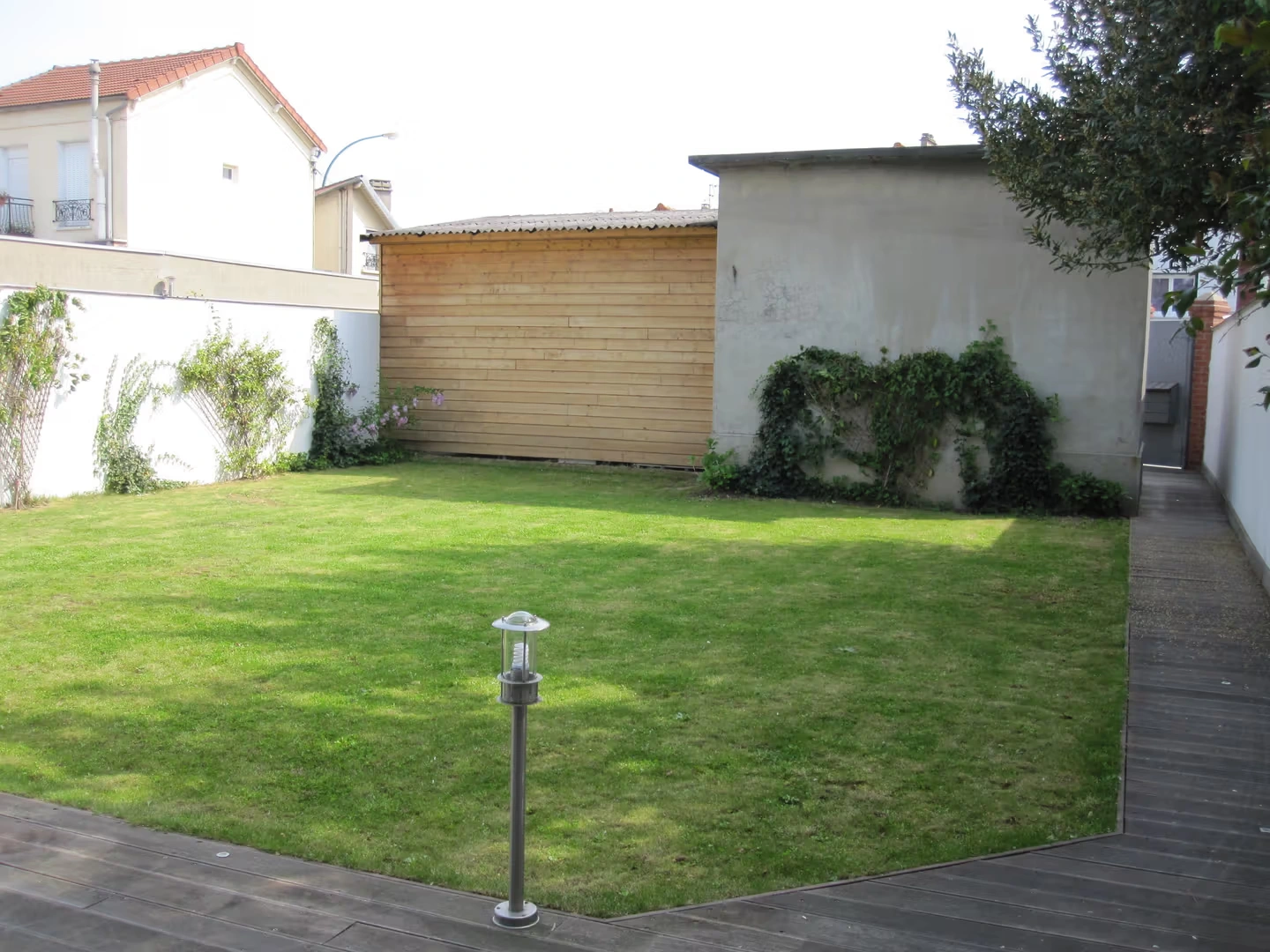 Originalgarten mit Rasenfläche, Holzdeck und freiem Durchgang rechts